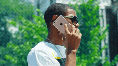 Young Man Wearing Sunglasses Talking On IPhone GIF