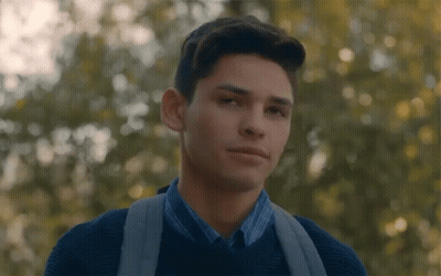 Young Man With Backpack Looking At Camera In Trees GIF
