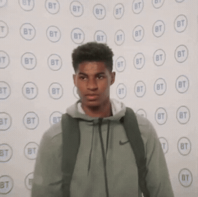 Young Man With Backpack Near BT Logos Wall GIF