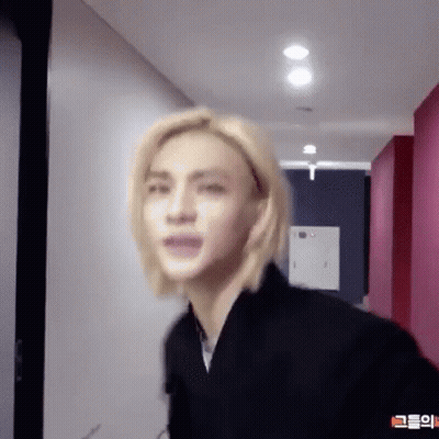 Young Man With Blonde Hair Standing In Hallway GIF