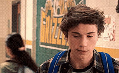 Young Man With Blue Backpack Walking Down Hallway GIF