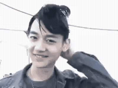 Young Man With Bun Smiling Touching Head GIF