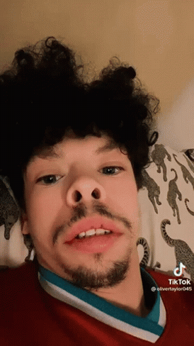 Young Man With Curly Hair And Beard Laying On Bed GIF