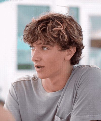 Young Man With Curly Hair In Gray Shirt GIF