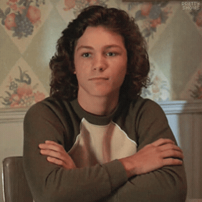 Young Man With Curly Hair Sitting Crossed Arms GIF