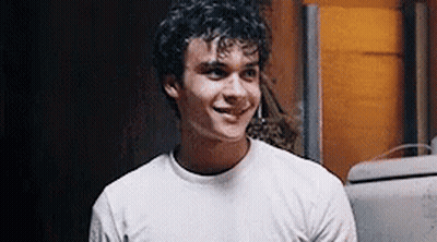Young Man With Curly Hair Smiling In White T-Shirt GIF