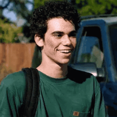 Young Man With Curly Hair Smiling Next To Blue Truck GIF