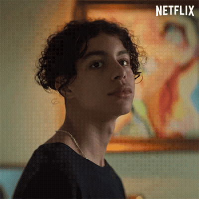 Young Man With Curly Hair Standing In Front Of Painting GIF