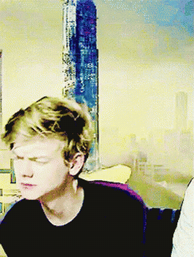 Young Man With Eyes Closed Sitting In Front Of Yellow Wall GIF