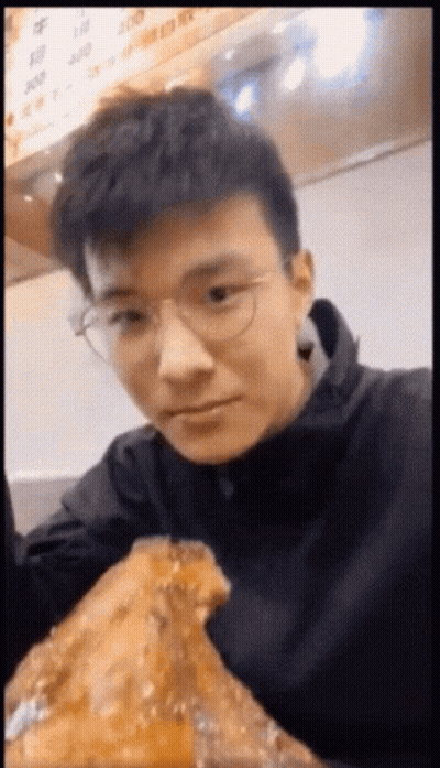 Young Man With Glasses Eating Large Piece Of Food GIF