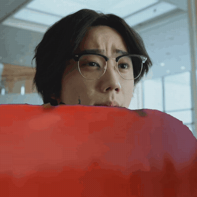 Young Man With Glasses Looking Over Red Blanket GIF