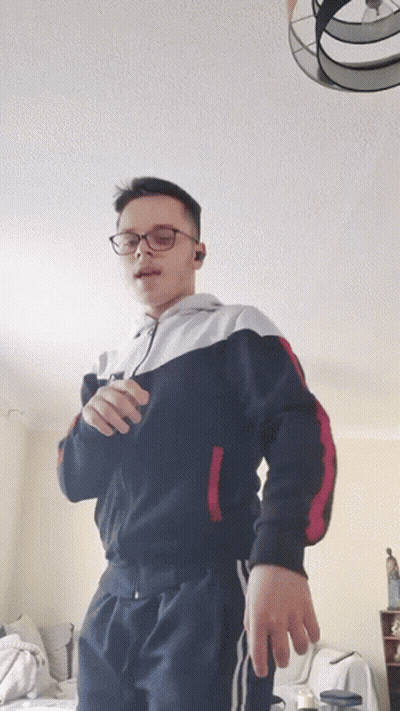 Young Man With Glasses Standing In Living Room GIF
