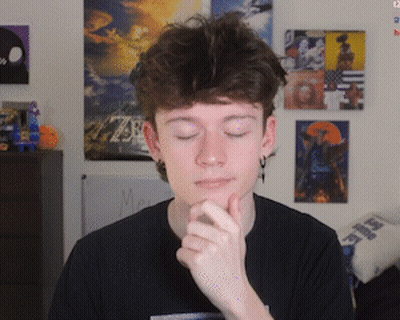 Young Man With Hand On Chin In Front Of Picture Wall GIF