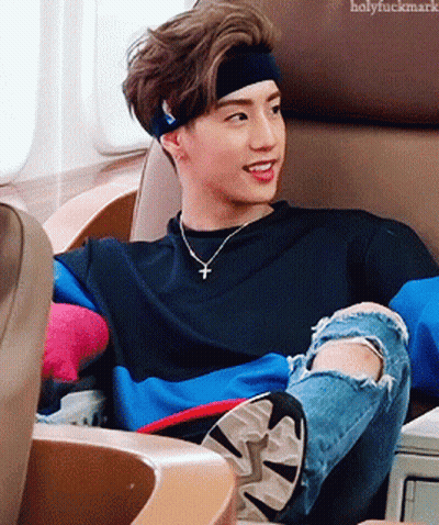 Young Man With Headband And Necklace Sitting In Chair GIF