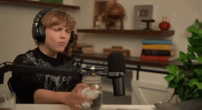 Young Man With Headphones Sitting At Microphone Holding Jar GIF