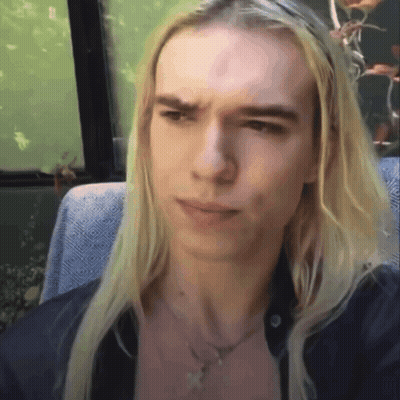 Young Man With Long Blonde Hair Sitting In Chair GIF