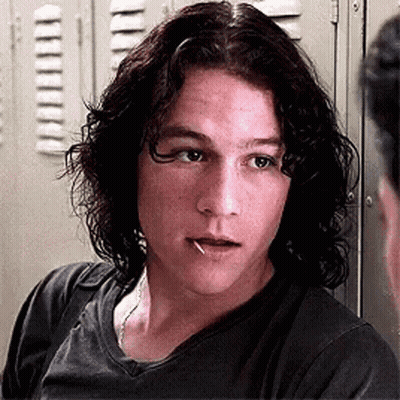 Young Man With Long Curly Hair Standing In Front Of Lockers GIF