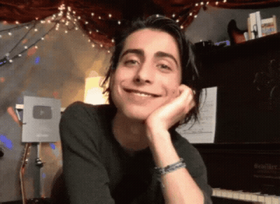 Young Man With Long Hair Smiling At Piano GIF