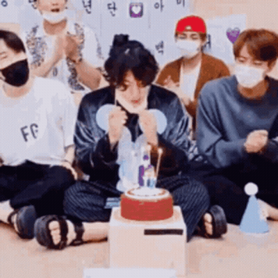 Young Men In Face Masks Sitting Around Cake GIF