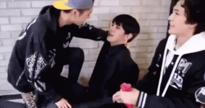 Young Men Sitting And Talking In Front Of Brick Wall GIF