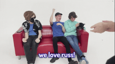 Young Men Sitting On Red Couch One Wearing Mask GIF