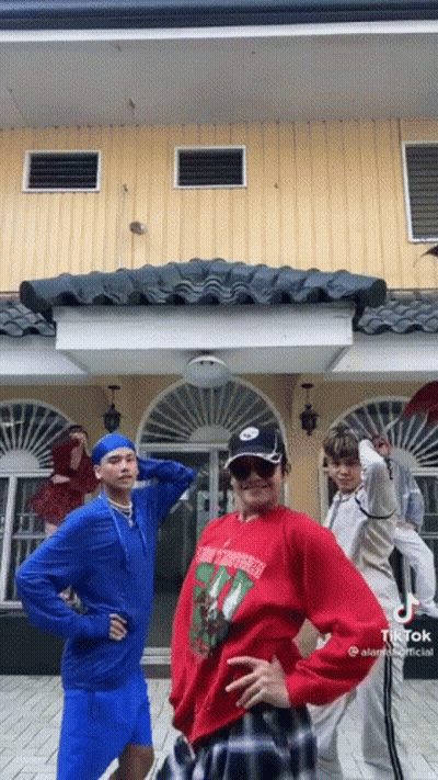 Young Men Standing In Front Of Yellow Building GIF