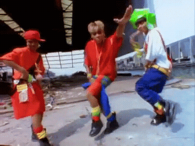 Young People Dancing In Colorful Outfits In Front Of Building GIF
