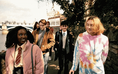 Young People Walking Down Sidewalk Next To River GIF