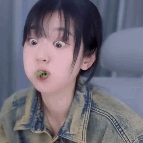 Young Woman In Denim Jacket Making Funny Face Eating Green Leaf GIF
