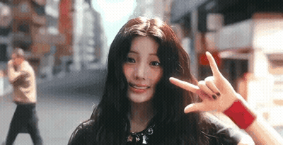 Young Woman Making Peace Sign On City Street GIF