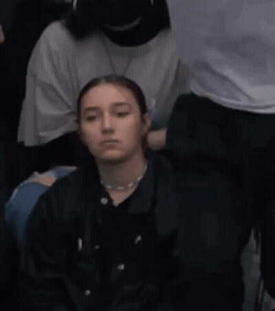 Young Woman Sitting In Crowd GIF