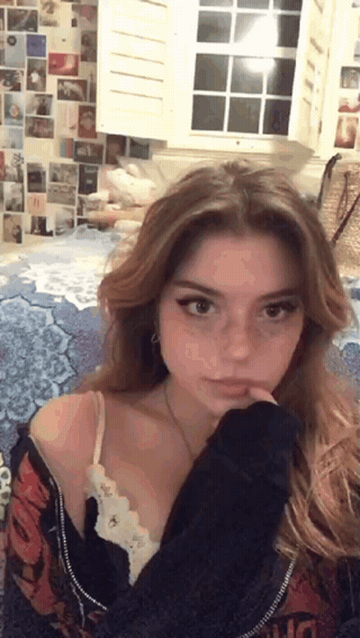 Young Woman Sitting On Bed By Window GIF