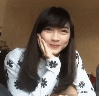 Young Woman Sitting On Bed With Hand On Face GIF