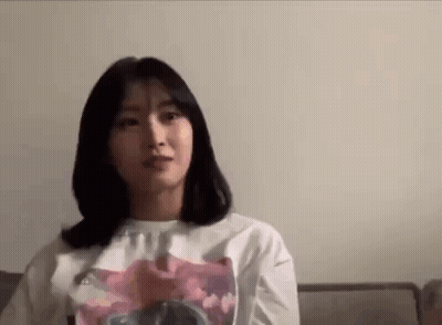 Young Woman Sitting On Couch In White T-Shirt GIF