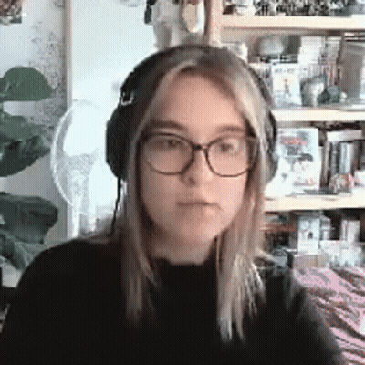Young Woman With Glasses And Headphones In Front Of Bookshelf GIF