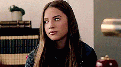 Young Woman With Long Hair Sitting In Room With Lamp GIF