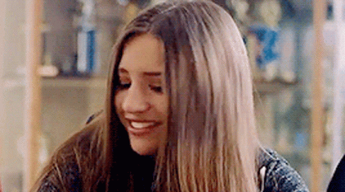 Young Woman With Long Hair Smiling At Table GIF