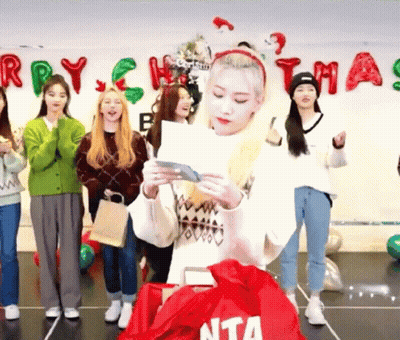 Young Women Standing In Front Of Christmas Banner GIF